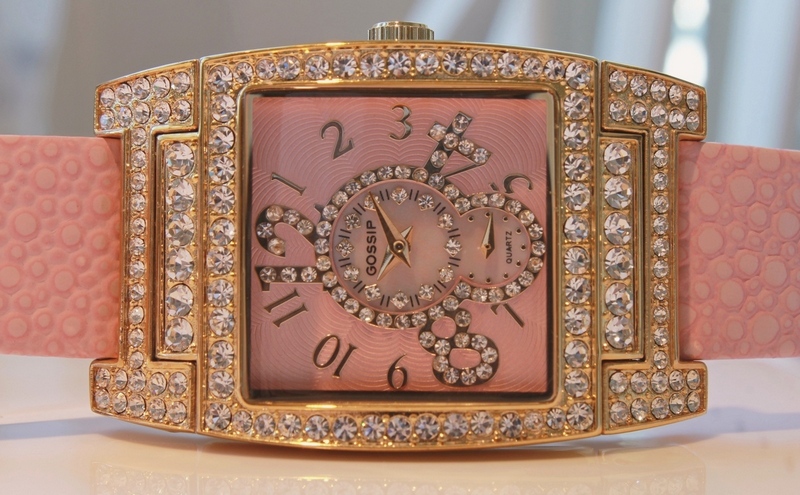 Pave-set crystal accents gleam on both the square-shaped case and mother-of-pearl dial, highlighted with a keyhole design. Color coordinated with a matching dial and pink leather band. From Gossip Fashion Watches.